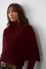 Capita de tejido de punto acanalado en color bordó, con cuello alto y diseño sin mangas con aberturas laterales.