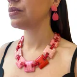 Collar corto con cadena de eslabones cuadrados de resina en tonos rosa y rojo. Cierre con mosquetón y cadena para regular el largo.