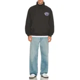 Campera anorak negra con cuello alto y cierre de botones a presión. Presenta un bolsillo tipo canguro en la parte delantera y un estampado ovalado en el pecho con la palabra "Critical" y "Slide Society" en color lila. El dobladillo es elástico.