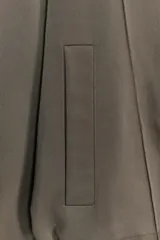 Cazadora estilo bomber color gris, con cuello subido, manga larga, bolsillos delanteros de vivo y cierre frontal con cremallera. Presenta bajo ajustable con cordones elásticos laterales.