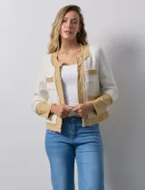 Chaqueta Nanette de tejido tweed y denim color blanco con cuello a la base y abertura central. Delantera con bolsillos, puño con aplique de botones metálicos y terminación desflecada.