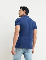 Remera polo azul marino de manga corta, con cuello y tapeta de dos botones. Presenta aberturas laterales en el dobladillo.