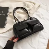 Cartera tipo bolso de mano color negro, con doble asa superior y dos bolsillos frontales con solapa y cierre de botón a presión.