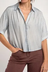 Camisa oversize celeste y beige con rayas verticales, cuello camisero, mangas cortas y cierre frontal con botones.