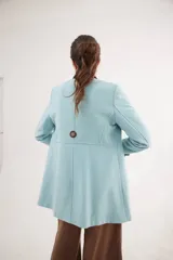 Tapado corto de paño de lana en color celeste, con cuello mao en pana marrón, botones forrados en contraste y cinta de terciopelo aplicada. Presenta una silueta entallada con bolsillos delanteros.