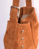 Cartera tipo shoulder bag de cuero gamuzado color suela, con diseño de flecos en la base y detalle de tachas metálicas en los laterales. Cuenta con correa regulable y forro interior.