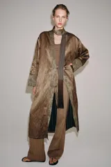 Kimono de la colección ZW de Zara, confeccionado en tejido marrón con acabado satinado. Presenta solapas anchas en tono verde con estampado estilo jacquard y flecos largos colgantes en el frente. Cuenta con mangas largas con puños estampados y bolsillos laterales ocultos.