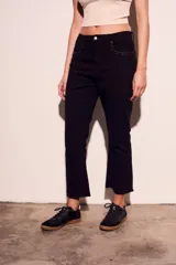 Pantalón de jean negro con corte flare, tiro medio y detalles de tachas plateadas en los bolsillos delanteros.