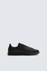 Zapatilla de estilo minimalista confeccionada en piel, con diseño de cordones ocultos, horma redonda y suela a tono.
