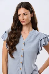 Camisa de lino y viscosa color beige, con cuello mao, escote en V y botones frontales de madera. Presenta mangas cortas con volados delicados.