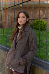 Chaquetón de lana color bordó con diseño de espiga y motas blancas. Tiene solapa, doble abotonadura frontal, mangas largas con detalle de correa y hebilla en los puños.