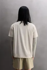 Camiseta de entrenamiento regular fit color beige, confeccionada en combinación de tejidos técnicos ligeros y elásticos con tecnología Quick Dry nivel 2. Presenta cuello redondo, manga corta, acabados con costuras planas y termofijadas, y detalle de logo estampado en el bajo.