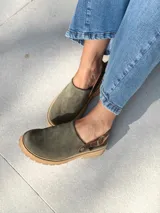 Zuecos de cuero color verde seco, con hebilla lateral y suela de goma.