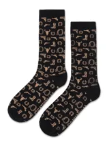 Medias largas negras con estampado de motivos western en color tostado, que incluye revólveres, botas, herraduras y calaveras de toro.