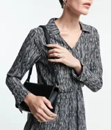 Vestido corto camisero de crepé con estampado abstracto en blanco y negro, cuello con solapa, mangas largas y lazo en la cintura.