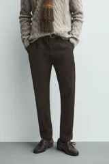 Pantalón chino de corte ajustado, color beige, con bolsillos laterales y bolsillos traseros de vivo. Cuenta con cierre frontal de cremallera y botón.