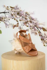 Sandalias chatitas de cuero en tono nude, con diseño de tiras cruzadas en el empeine y elástico en el talón para mayor ajuste. Presentan una plantilla acolchada y detalles en cuero charolado en la parte posterior.