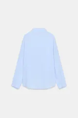 Camisa de manga larga color celeste claro, con cuello solapa y cierre frontal de botones.
