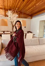 Ruana tejida color borgoña con flecos y bolsillos.