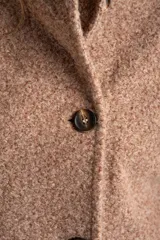 Tapado de paño color tostado, con cuello alto y cierre frontal de botones. Diseño de corte recto y largo a la cadera.