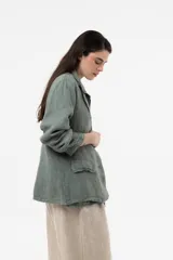 Chaqueta de lino verde militar de calce relajado, con solapa clásica, cierre frontal con dos botones grandes y bolsillos delanteros con solapa.