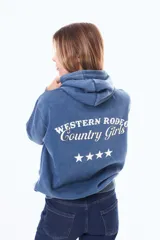 Buzo con capucha de felpa en color azul con efecto lavado. Presenta una estampa en la espalda con el texto 'WESTERN RODEO Country Girls' y cuatro estrellas blancas alineadas debajo.