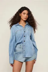 Camisa de jean celeste de corte clásico, con cuello, mangas largas, bolsillos frontales y cierre de botones.