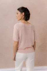 Cardigan tejido de manga corta color beige, con escote redondo amplio y abotonadura frontal con botones al tono. Presenta un calce relajado y terminaciones en rib en la cartera y el ruedo.