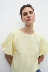Blusa amarilla con estampado floral, mangas cortas abullonadas y cuello redondo.