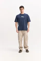 Pantalón cargo de fit baggy color beige, con piernas amplias, bolsillos laterales con tapa y costuras decorativas.