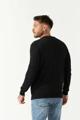 Sweater de punto color negro con escote en V, manga larga y puños acanalados. Presenta un pequeño logo bordado en el pecho.