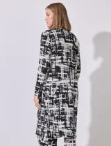 Cardigan largo de satén plisado con estampado abstracto en blanco y negro, marca Cyrus. Presenta aberturas laterales.