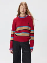 Sweater de punto cable con diseño a rayas horizontales en tonos marrón, amarillo y lila. Presenta cuello redondo acanalado, mangas largas con puños a juego y logo bordado en el pecho.