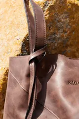 Bolso shopper de cuero vacuno marrón, con diseño de paneles geométricos y detalle de fleco decorativo colgando de un asa.
