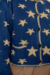 Saco abotonado de punto con diseño de estrellas en contraste, cuello redondo, mangas largas y dos bolsillos frontales. Presenta bordes con terminación enrollada.
