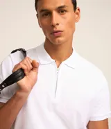 Remera polo blanca de algodón con cuello inglés y cremallera.