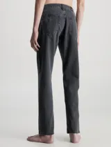 Jeans de denim rígido de algodón, color negro descolorido, con talle medio a bajo, pierna recta y bragueta con cremallera.