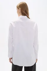 Camisa blanca de poliéster, corte holgado, con cuello camisero y cierre frontal con botones.
