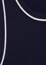 Top de punto fino sin mangas, con cuello redondo y diseño entallado. Presenta un color azul marino con detalles de ribetes en contraste en color blanco en el cuello, sisas y ruedo.