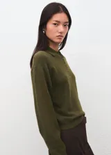 Jersey de punto verde militar con cuello polo y cierre frontal parcial con botones. Presenta manga larga y diseño de corte recto.