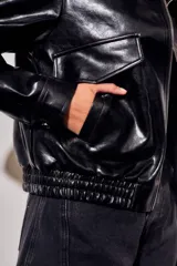 Campera bomber de cuero sintético negro, de corte oversize, con cuello solapa, cierre frontal metálico y bolsillos frontales con solapa.