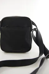 Morral bandolera de cuero genuino color negro, de diseño compacto y silueta rectangular, con bolsillo frontal con cierre y correa ajustable para el hombro.