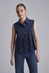 Camisa azul marino sin mangas con cuello clásico, abotonada al frente y detalle de plisados verticales en el pecho.