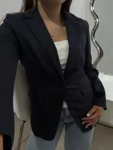 Blazer sastrero de corte clásico en color azul marino, con solapas de muesca, cierre frontal de un botón y bolsillos laterales con solapa.