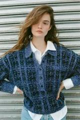 Jersey de punto con textura estructurada en tonos azules y negros, cuello polo con solapa, manga larga y cierre frontal parcial con botones.