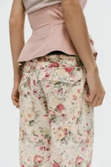 Jeans rectos de tiro medio con estampado floral multicolor sobre base blanca, trabillas para cinto, bolsillos delanteros y cierre frontal con cremallera y botón metálico.