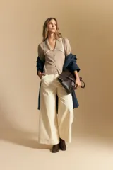 Pantalón largo color crema, tiro alto, de corte recto y ancho. Presenta costuras visibles en contraste y bolsillos delanteros.