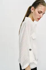 Blusa negra de cuello solapa y manga corta, con bolsillos con solapa en el pecho, bajo elástico y cierre frontal con botones.