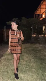 Cartera de mano con forma de hoja, confeccionada en cuero trenzado color naranja y negro. Asa corta trenzada de cuero negro.