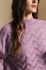 Sweater de punto color beige con diseño geométrico en relieve, cuello alto y mangas largas con puños acanalados.